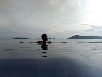 Silhouette person swimming in sea against sky
