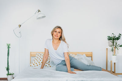 Portrait of a smiling young woman sitting on bed