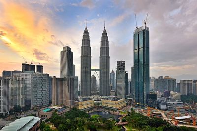 Modern buildings in city against sky during sunset