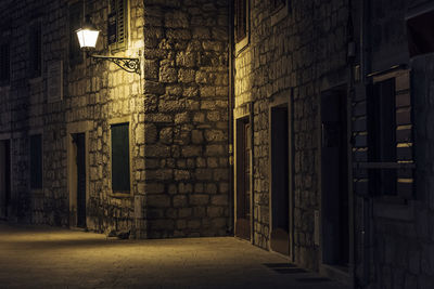 Empty alley amidst buildings in city at night