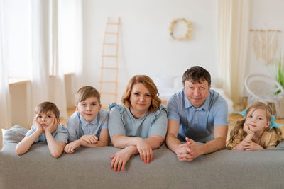 Big happy family posing near new purchased sofa in bright living room at home.