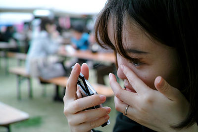 Close-up of woman analyzing eye while looking in mirror