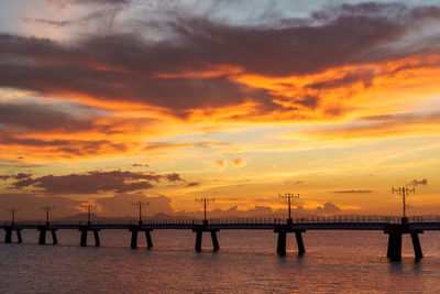 Pier over sea against orange sky