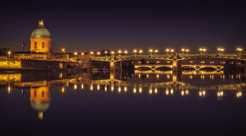 Illuminated bridge over river against sky at night