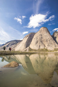 Reflection of two backpackers approaching steep mountains