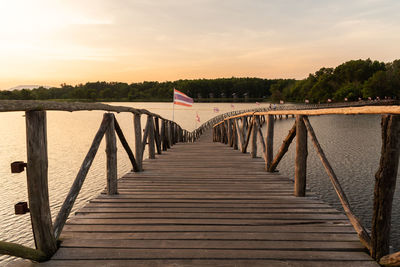 Wooden footbridge over lake against sky