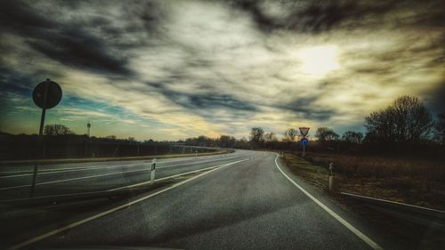 Empty road against cloudy sky