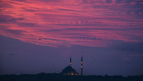 Silhouette mosque against cloudy sky during sunset