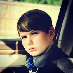 Close-up portrait of boy with headphones in car