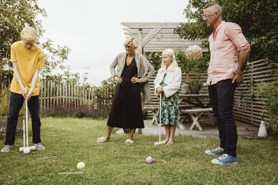 Pre-adolescent boy playing polo with family in back yard