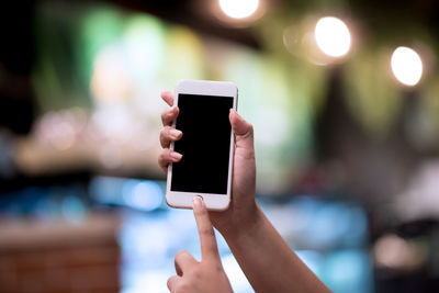 Close-up of human hand holding smart phone in city at night