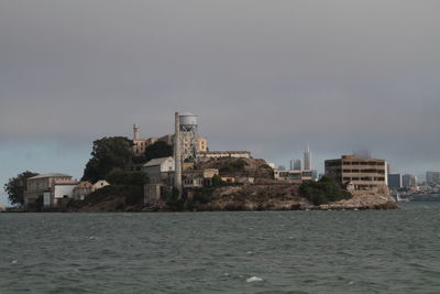 Buildings by sea against sky in city