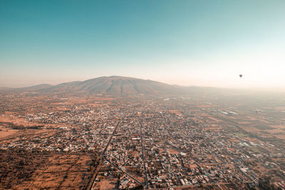 Aerial view of city and mountains against clear sky