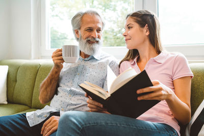 Friends using digital tablet while sitting on sofa at home