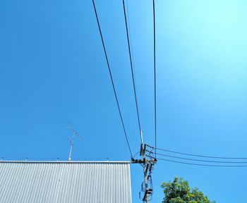 Low angle view of electricity pylon against blue sky