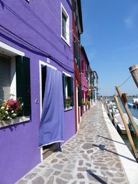 Street amidst buildings against blue sky