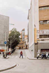 Man riding motorcycle on road against buildings in city