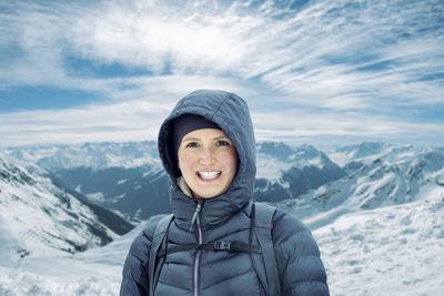 Portrait of smiling man standing on snowcapped mountain