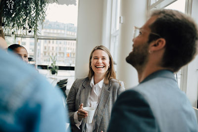 Smiling businesswoman having coffee with colleagues at creative workplace