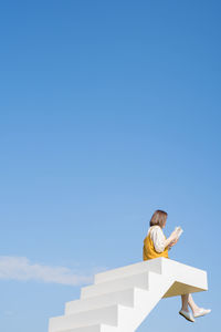 Asian woman relax and reading on white stair in flower garden on springtime vacation