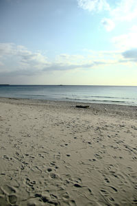 View of calm beach against cloudy sky