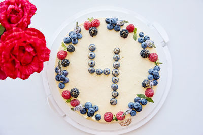 Birthday berries cake with number 4. decorated with fresh raspberries, blueberries, mint on yellow 