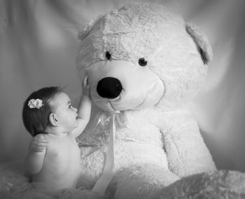 Cute girl with huge teddy bear against curtain
