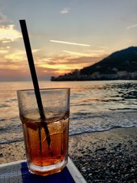 Close-up of beer glass on table at sunset