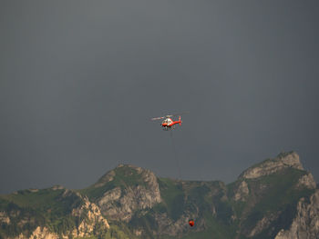 Scenic view of mountains against clear sky with firefighting helicopter 