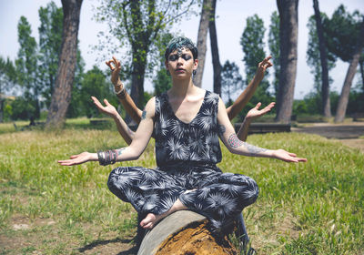 Young woman sitting by statue against trees