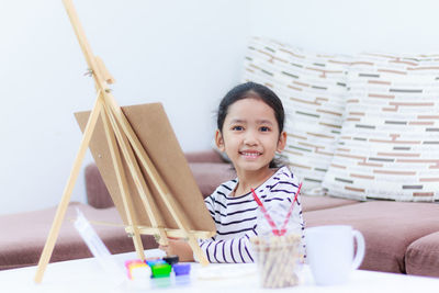 Portrait of girl painting on easel
