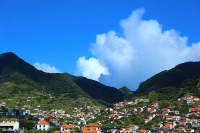 Panoramic view of townscape and mountains against blue sky