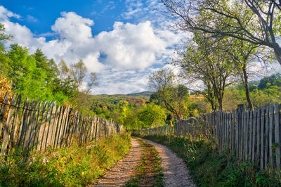Village road in autumn season with old fence in the countryside. infinity path.