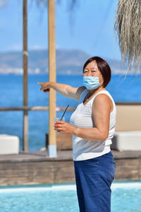 Woman standing by sea against blue sky