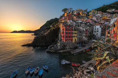 Panoramic view of sea and buildings against sky at sunset