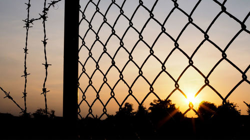 Close-up of silhouette fence against sky during sunset