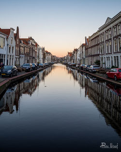 Boats moored in river against buildings in city at sunset