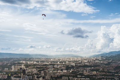 Aerial view of townscape against sky with paraglider