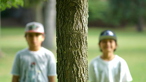 Portrait of boy standing on tree trunk