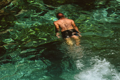 Rear view of shirtless man swimming in sea