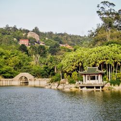 House by lake and buildings against sky