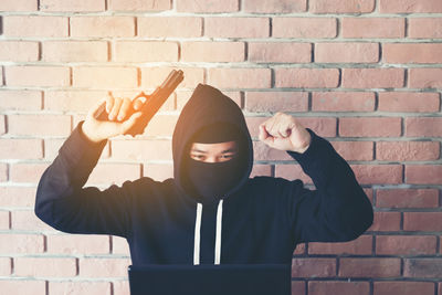 Mid adult man standing against brick wall