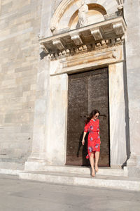 Full length of woman standing against door of building