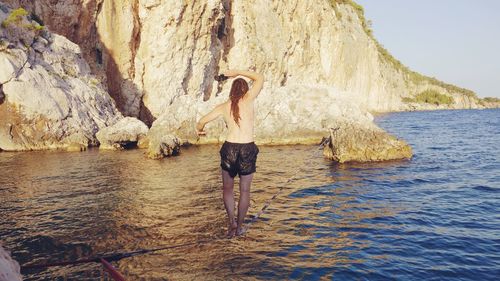 Low section of man standing on sea shore against sky