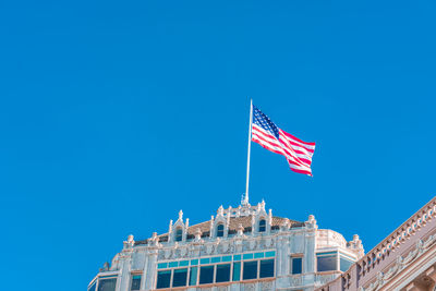 Low angle view of flags against clear blue sky