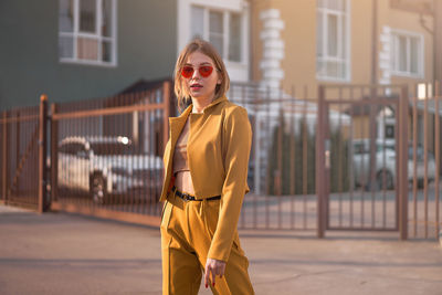 Woman wearing sunglasses standing against building in city