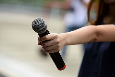 Midsection of woman holding microphone