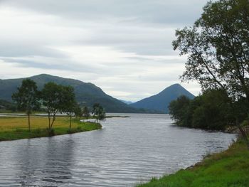 Scenic view of river by mountains against sky