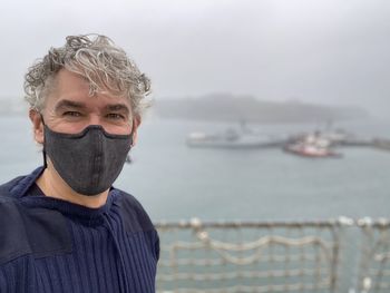 Portrait of man wearing mask standing against sea