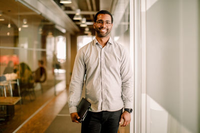 Portrait of smiling sales executive standing in corridor at work place